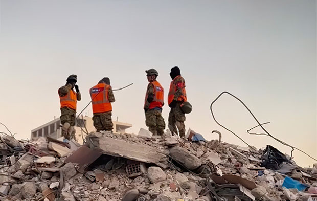 Front-line workers standing on top of rubble