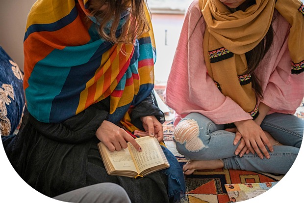 Two women sitting next to each other reading the Bible